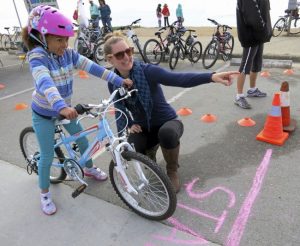 Kids and adults alike need to learn and practice bicycle safety. Here a girl learns the rules of the road at Open Streets Santa Cruz County 2013 on West Cliff Drive. (Karen Kefauver -- Contributed)